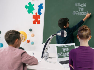 EV - Transformer HD - Back view of schoolboy writing on chalkboard while classmate studying at desk